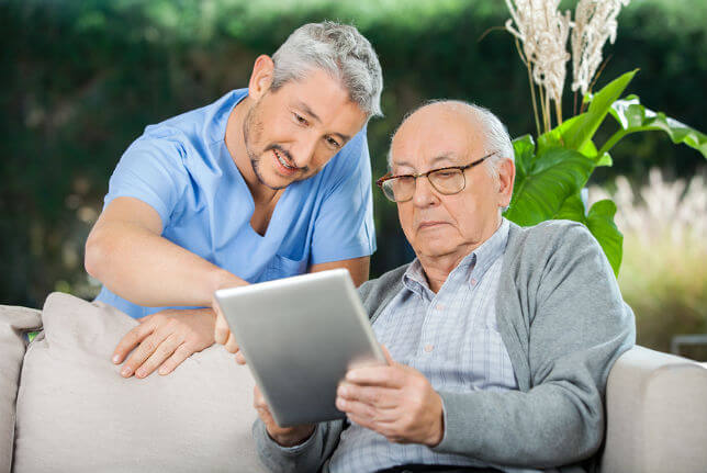Caretaker and Elder on Tablet - Telemedicine