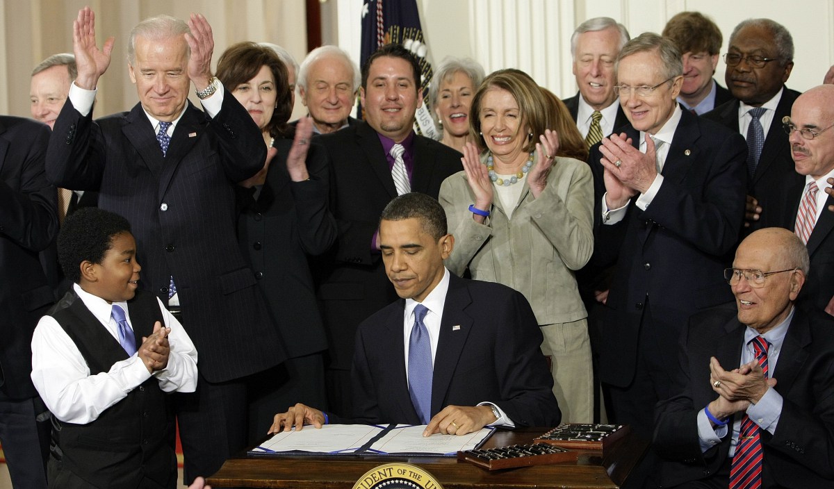 FILE - In this March 23, 2010, file photo, participants applaud in the East Room of the White House in Washington, Tuesday, March 23, 2010, as President Barack Obama, flanked by Macelas Owens of Seattle, left, and Rep. John Dingell, D-Mich., right, signs the health care bill. Americans may not be all that crazy about President Barack Obamaís health care law, but a new poll shows they donít see it going away. The Associated Press-GfK poll finds that about 7 in 10 Americans think the overhaul law will go into effect fully, with some changes, ranging from minor to major alterations. Behind the president, from left are, Senate Majority Whip Richard Durbin of Ill., Vice President Joe Biden, Vicki Kennedy, widow of Sen. Ted Kennedy, Rep. Sander Levin, D-Mich., Ryan Smith of Turlock, Calif., Health and Human Services Kathleen Sebelius, House Speaker Nancy Pelosi of Calif., House Majority Leader Steny Hoyer of Md., Senate Majority Leader Harry Reid of Nev., Rep. Patrick Kennedy, D-R.I., House Majority Whip James Clyburn of S.C., and Rep. Henry Waxman, D-Calif. (AP Photo/J. Scott Applewhite, File) ORG XMIT: WX106