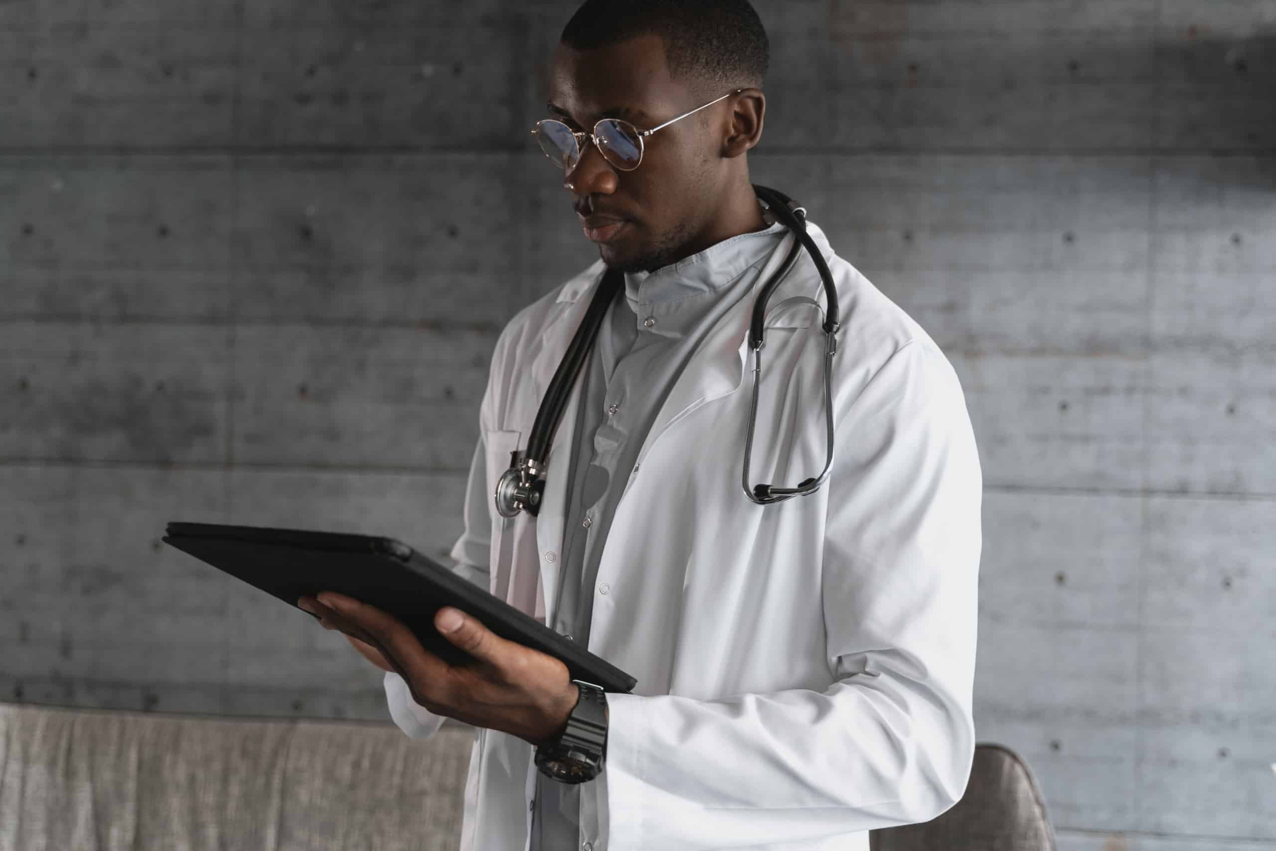 Man in white coat holding black tablet computer