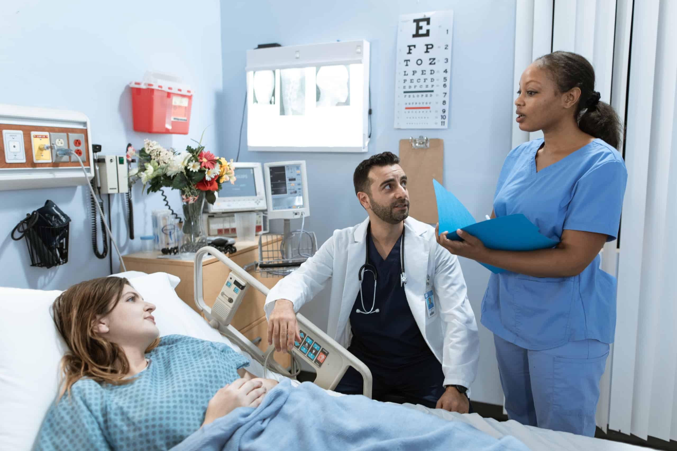 Man in white scrub suit massaging man in blue scrub suit